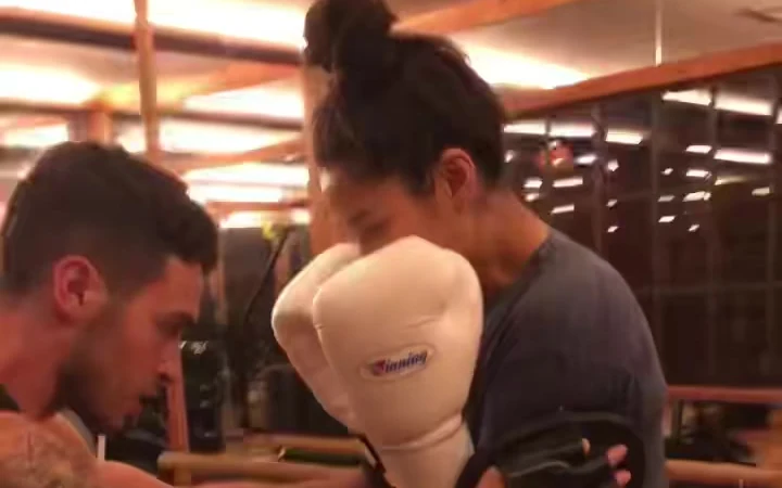 Eric holding pads for Shay Mitchell during a boxing session